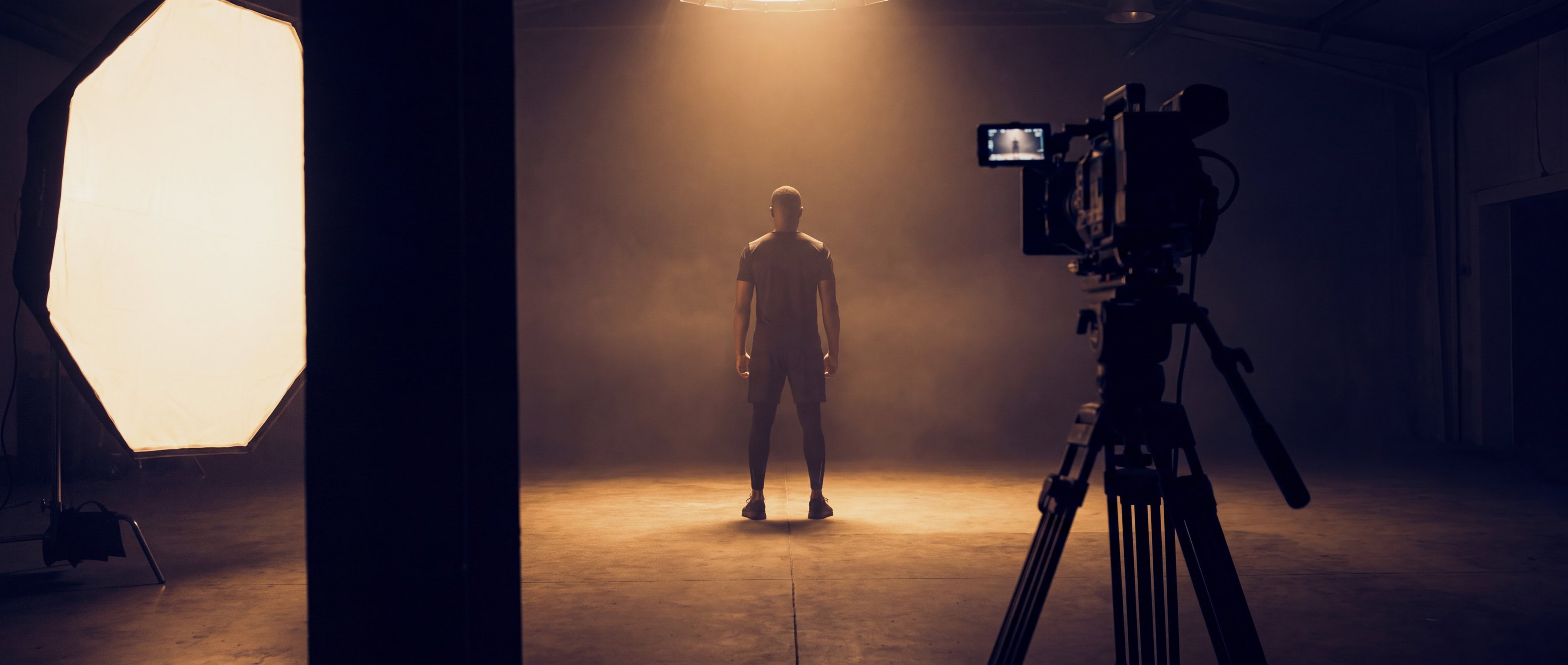 Kampagnenaufnahme im Studio: Sportler im Lichtkegel zwischen Softbox und Kamera